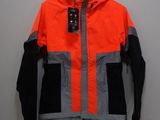 une veste orange et noire suspendue à un cintre accroché au mur