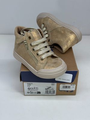 Les baskets dorées des enfants sont posées sur une boîte en carton.
