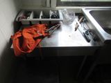 a kitchen with a sink and a counter with utensils on it