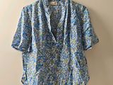 une chemise bleue à motifs floraux suspendue à un cintre contre un mur