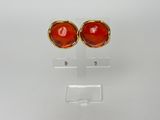 une photo d'une paire de boucles d'oreilles en verre rouge posées sur un présentoir transparent