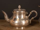 two silver teapots sitting on a wooden table