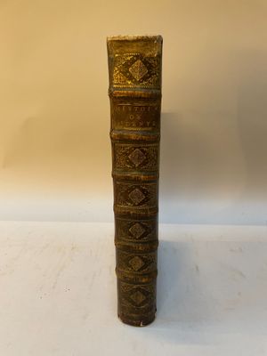 un vieux livre à la couverture dorée posé sur une table blanche
