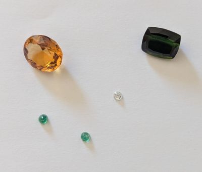 trois pierres précieuses de couleurs différentes sur un fond blanc, dont une verte et une marron