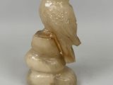 an image of a statue of an owl sitting on a rock