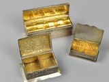 three silver and gold jewelry boxes sitting next to each other on a white surface