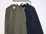 two jackets hanging on a clothes rack in a white room