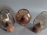 three glass vases sitting on top of a wooden stand