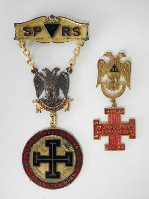 a group of three medals including a cross, eagle, and shield