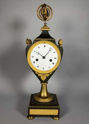 une horloge ancienne ornée de motifs dorés et noirs, posée sur un socle