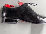 pair of black leather shoes with red soles hanging on a wall
