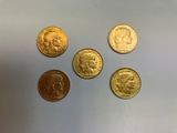 quatre types différents de pièces d'or sur une surface blanche