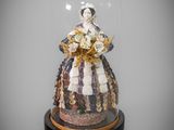 figurine représentant une femme en robe, sous une cloche en verre