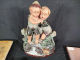 a figurine of two children sitting on a rock