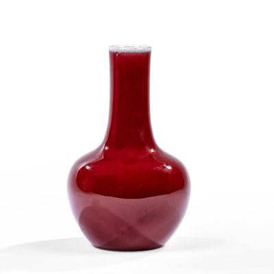 un vase rouge posé sur une surface blanche, avec un fond blanc