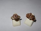 two gold rings with a pink stone on top of them