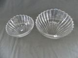 une paire de bols en verre transparent en forme de coquillage posés sur un tissu blanc