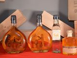 three bottles of liquor sitting on a table with a red table cloth