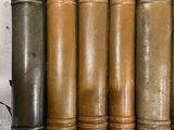 several old books are lined up in a row on a shelf