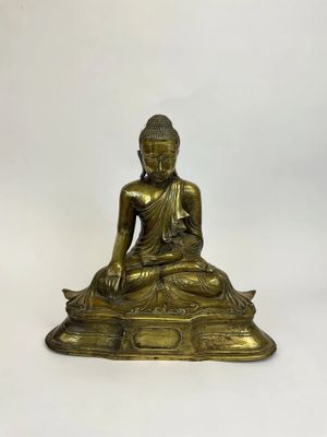 a brass statue of a buddha sitting on a rock