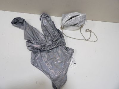 un body argenté posé sur une table, à côté d'un sac à main