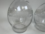 two glass vases sitting on a table with a white background