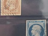 three stamps of different sizes and colors are on display in a glass case