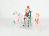 trois figurines représentant une femme assise sur une chaise