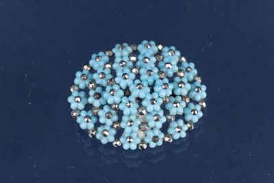 un gros plan d'un objet orné de perles bleues posé sur une surface noire