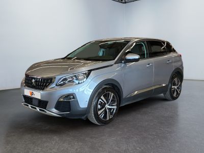 La voiture argentée est garée dans une grande pièce au sol noir.