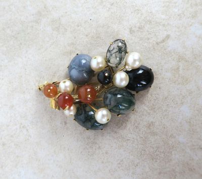 a close up of a brooch with pearls and gems