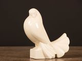 a white bird statue sitting on top of a wooden table
