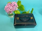 a small black box with a handle and a flower in a vase