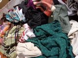 a pile of clothes sitting on the floor next to a bed