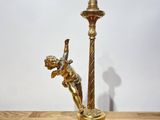 a gold candle holder on a wooden table with a candle