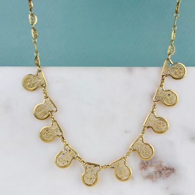 une photo d'un collier avec une pièce en or posé sur une surface en marbre
