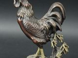 statue of a rooster standing on a rock with a branch in its beak