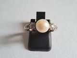 une image représentant une bague ornée d'une perle, posée sur un écrin noir