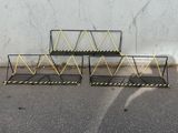 three black and yellow metal racks on the ground