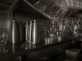 bottles and glasses on a shelf in a kitchen with a lot of clutter