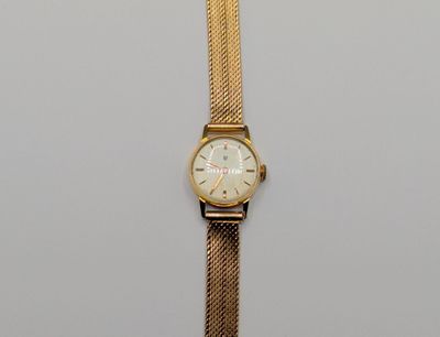 a close up of a gold watch on a white surface