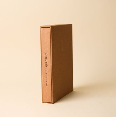 un livre brun posé sur une table à côté d'un mur blanc