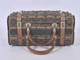 une valise marron et noire posée sur une surface blanche
