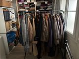 a closet full of coats and jackets hanging on a rack