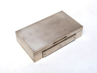un vieux étui à cigarettes en argent posé sur une table blanche