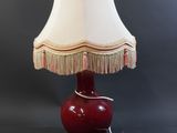 une image représentant une lampe rouge surmontée d'un abat-jour blanc