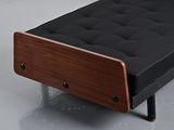 a black futon bed with a wooden frame on a grey floor