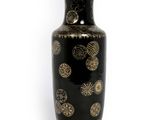 un vase noir orné de motifs dorés sur fond blanc