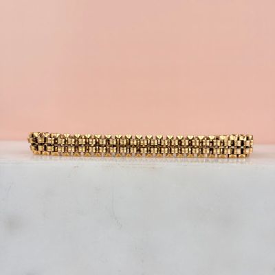 a close up of a gold bracelet on a marble surface