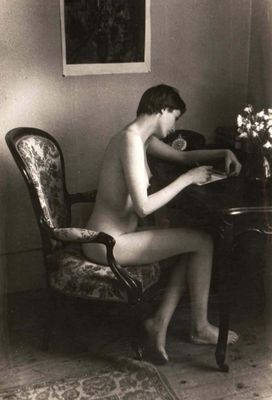 a naked man sitting at a desk with a vase of flowers